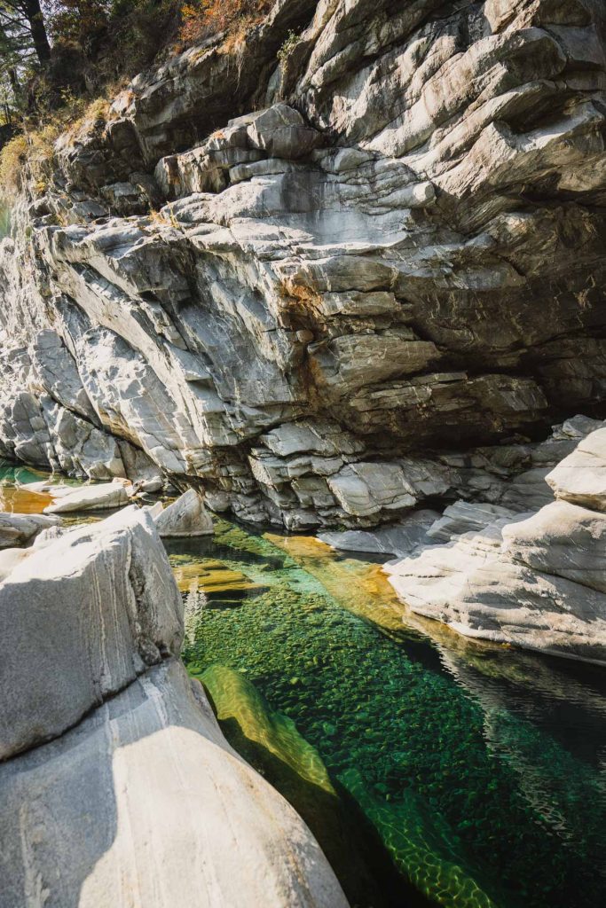 Fel groen, helder water tussen gladgesleten witte rotsen in de Maggia bij Ponte Brolla.